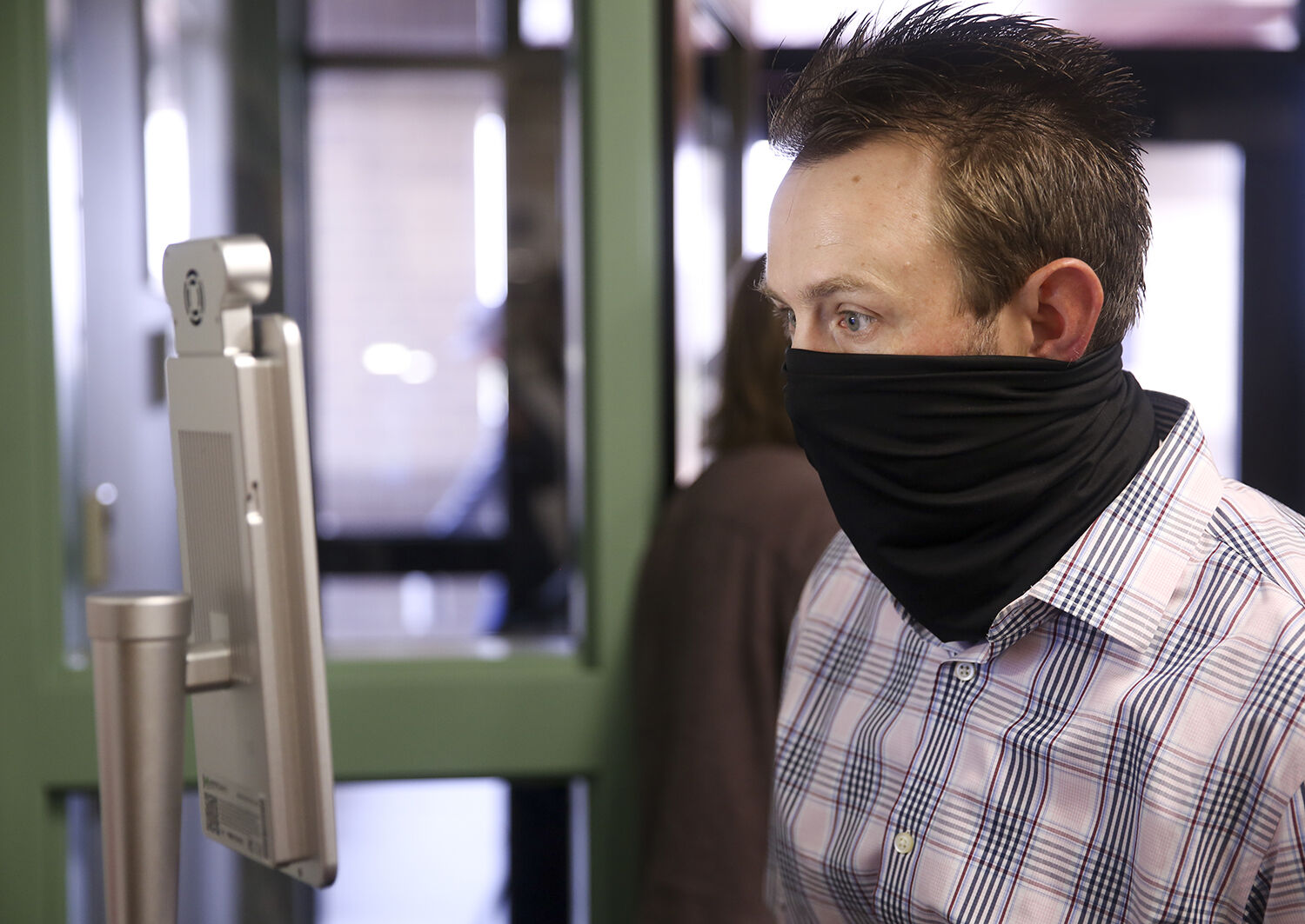 Band teacher Jason Bennett checks his temperature using the machine